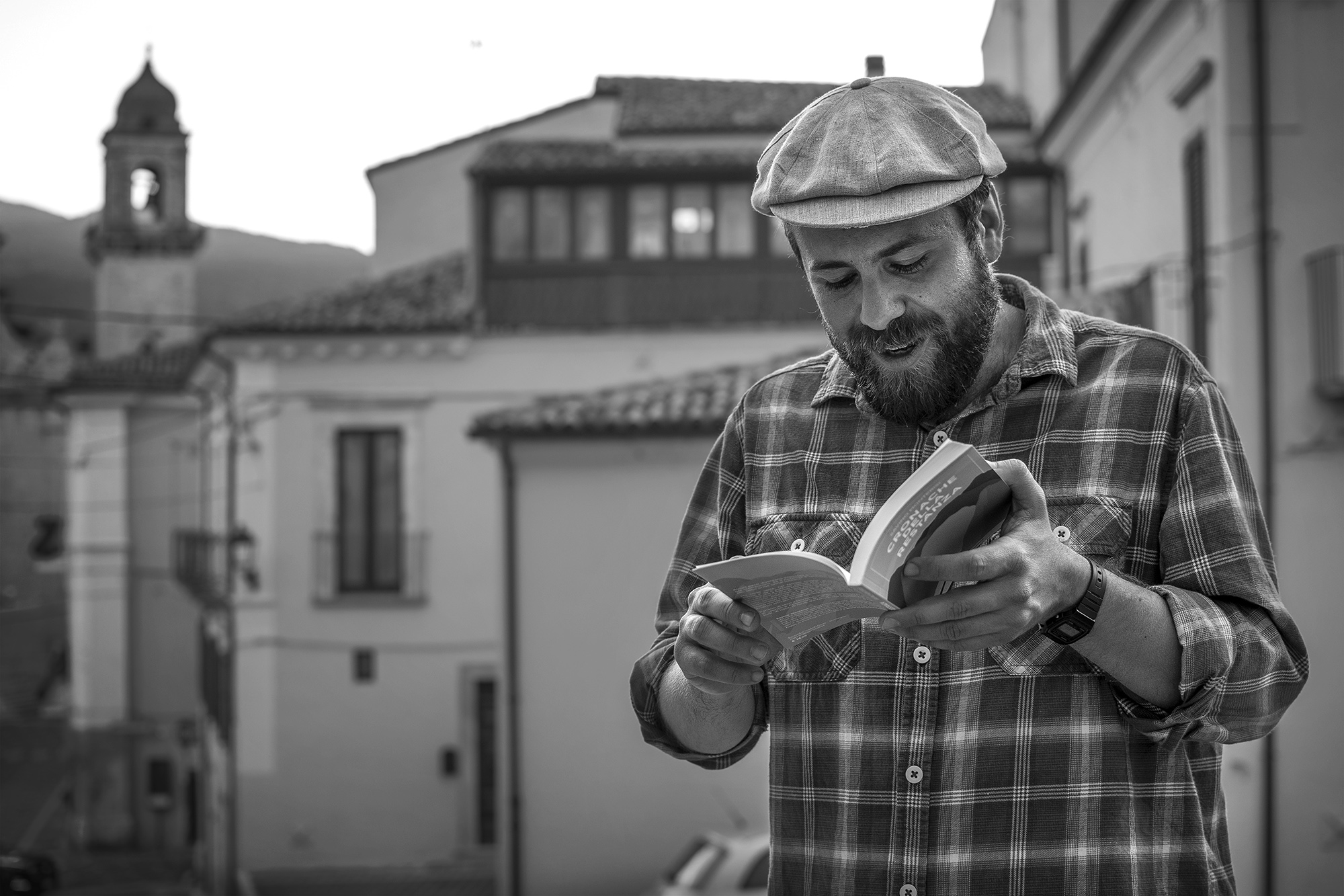 foto in bianco e nero di Paolo Fiorucci mentre legge un libro in un borgo